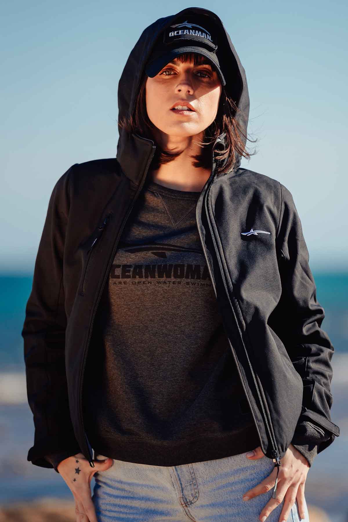 Woman at the beach wearing a jacket and a cap from oceanman